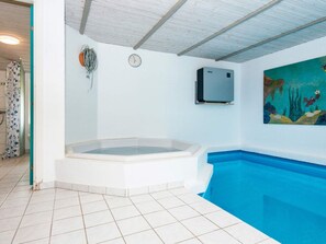 Ein Schwimmbecken mit Whirlpool, einer Uhr und einer Klimaanlage an der Wand.