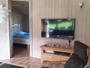 A room with a bed, a wooden desk, a chair, a television, and a door leading to another room. - 4 Star Holiday Home in Nordborg (Nordborg)