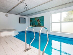 An indoor swimming pool with metal ladders, a clock, and a painting on the wall. - 4 Star Holiday Home in Nordborg (Nordborg)