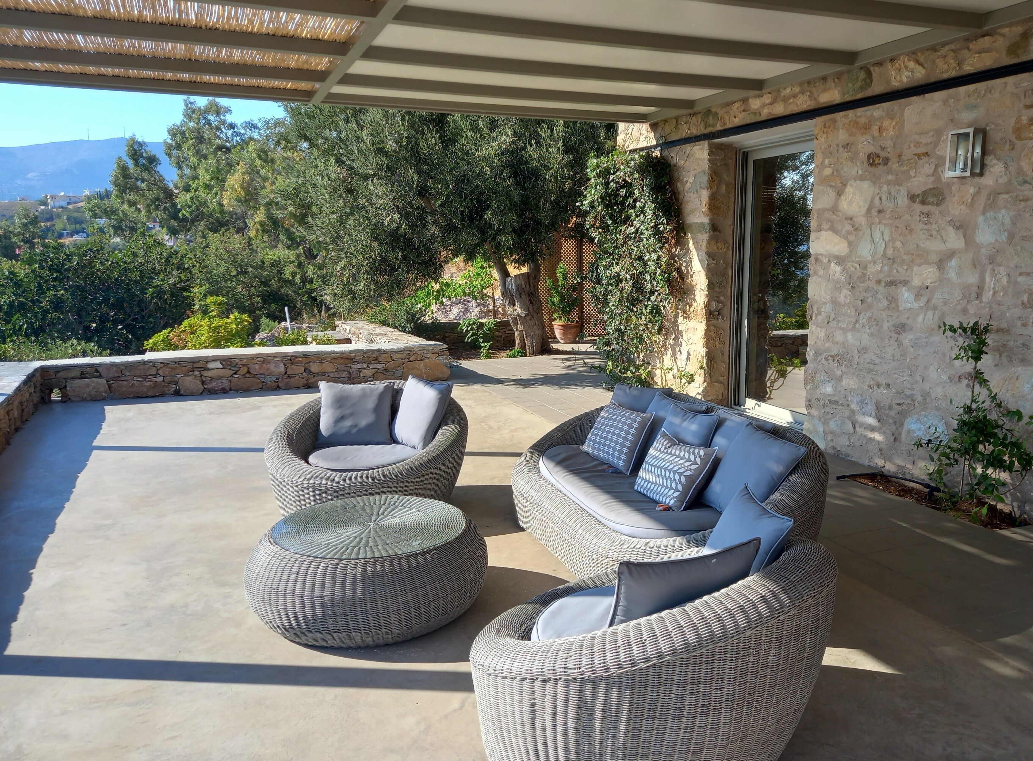 An outdoor patio area with wicker furniture and a stone wall.