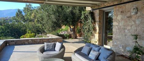 An outdoor patio area with wicker furniture and a stone wall.