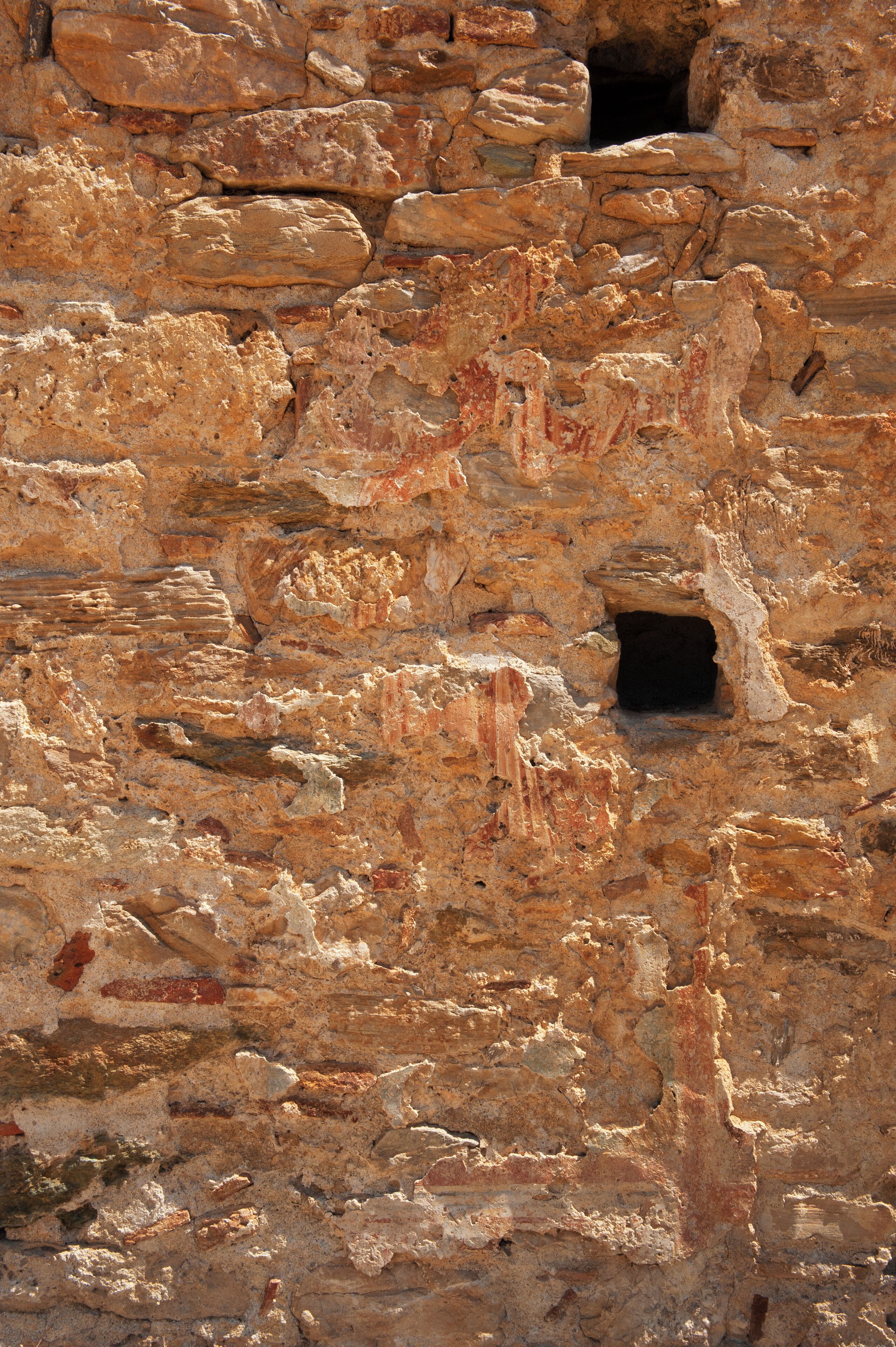 A close-up of a stone wall with a small opening.