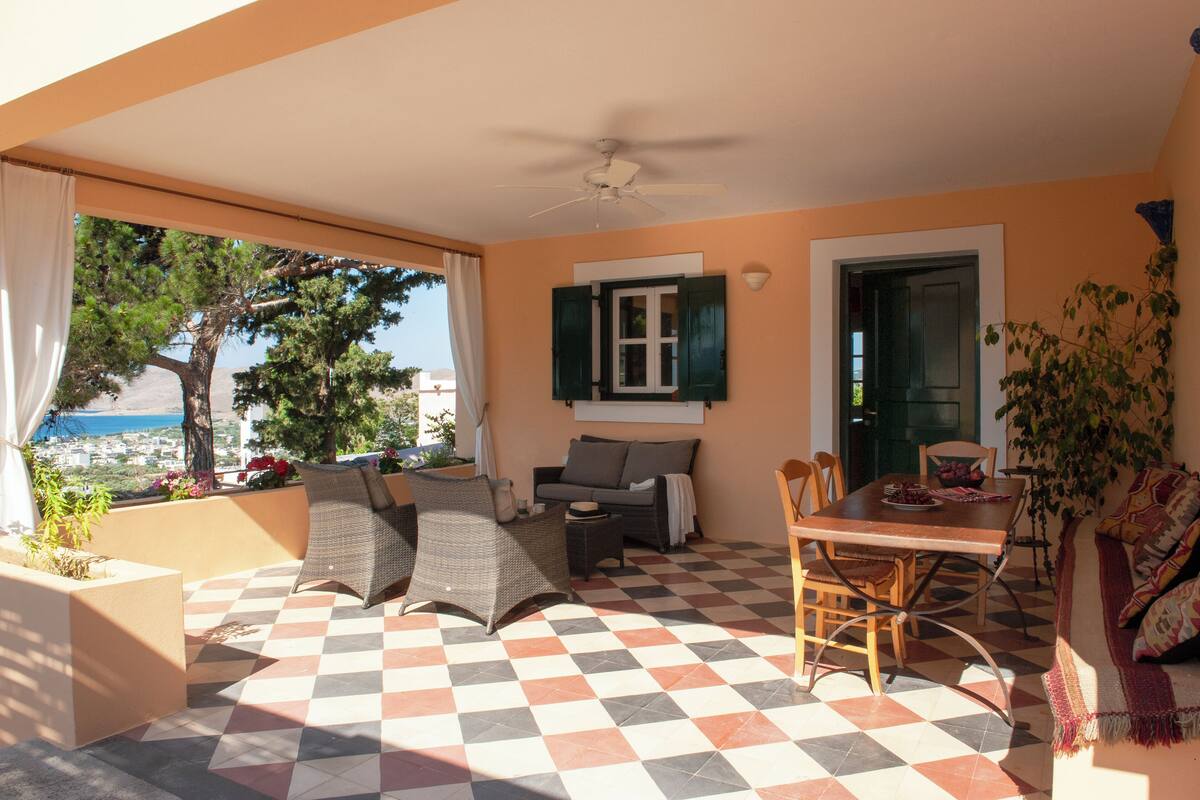 Un patio soleado con suelo a cuadros, una mesa de comedor, sillas, un sofá y un ventilador de techo.