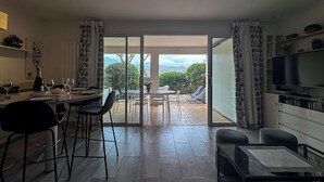 Una sala de estar moderna con comedor, televisor en la pared y vistas al exterior.