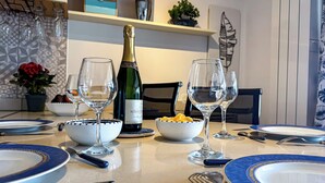 Una mesa de comedor dispuesta con platos, ensaladeras, copas de vino y una botella de champán.