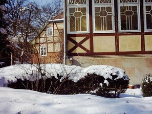 A traditional half-timbered house with snow-covered bushes in front. - at Bunge Heath Farm (Uelzen)
