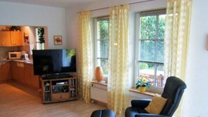 A living room with a TV, black armchair, and wooden flooring. - Heinrich Tiarksstrasse 36 (Wangerland)