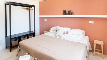 Un dormitorio con cama, mesitas de noche, una silla colgante y una estantería con adornos.