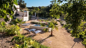 Ein Garten mit Pool, Liegestühlen und einer Pergola.