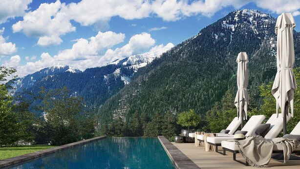 A pool with lounge chairs and umbrellas, surrounded by a mountainous landscape. - Apartment With Infinity Pool (Sankt Martin am Tennengebirge)