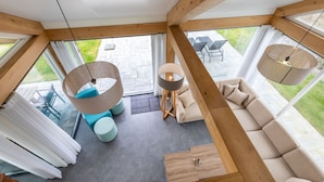 A modern interior with a wooden ceiling, a sofa, a round table, and a hanging light fixture. - Holiday Home in Renesse Near the Beach (Renesse)