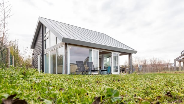 A modern house with a sloped roof, large glass windows, and a patio with outdoor furniture. - Holiday Home in Renesse Near the Beach (Renesse)