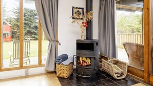A cozy room with a wood-burning stove, wicker baskets, and a view of the outdoors. - 5 Person Holiday Home in Gedser (Gedser)