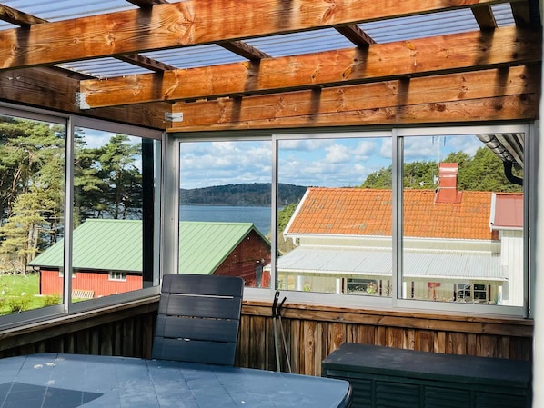 A room with a large window, wooden beams, and a view of a lake and buildings.