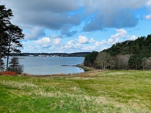 A lakeside view with a grassy area, trees, and a distant shoreline. - 4 Person Holiday Home in Hakenaset (Hakenäset)