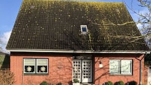Une maison de plain-pied en briques, avec un toit en pente, un petit porche à l’avant et une pelouse bien entretenue.