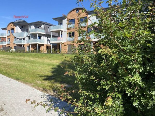 Um edifício residencial com várias varandas e um gramado.