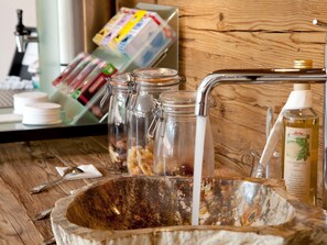 A wooden sink with a marble basin, a bottle of Darbo honey syrup, and jars with nuts and dried fruits. - Beautiful Suite Schwarzsee (Reith bei Kitzbuehel)