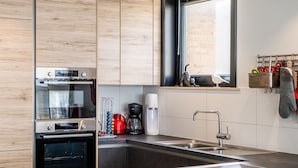 A modern kitchen with stainless steel appliances, a wooden countertop, and a window above the sink. - Apartment in Koksijde With Sea View (Koksijde)