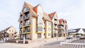 A multi-story residential building with balconies, a parking area, and a gated entrance. - Apartment in Koksijde With Sea View (Koksijde)