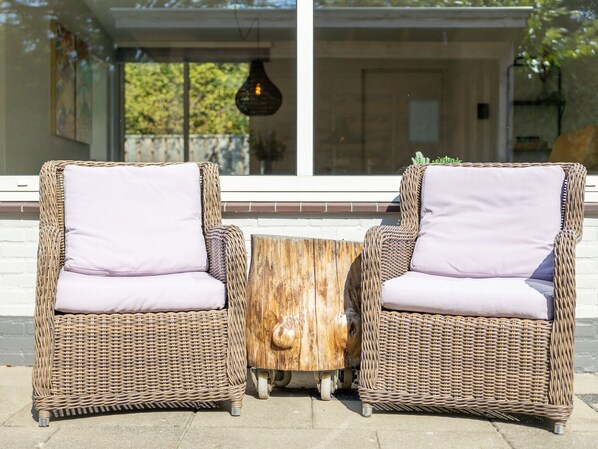 Two wicker chairs with cushions, a wooden coffee table, and a hanging light fixture.