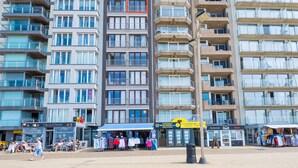 A multi-story hotel with balconies, a ground-level restaurant, and a visible storefront with clothing items. - Apartment on the 7th Floor With sea View (Middelkerke)