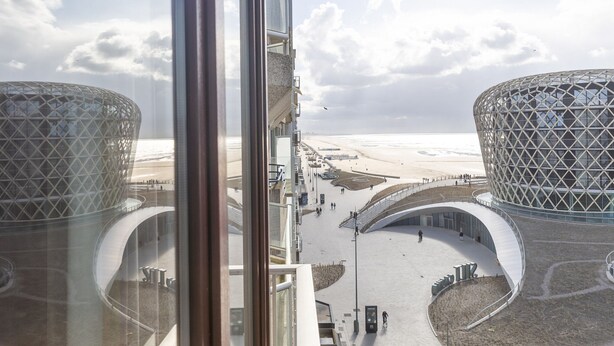 A modern architectural structure with a curved design, a pedestrian walkway, and a beach in the background. - Apartment on the 7th Floor With sea View (Middelkerke)