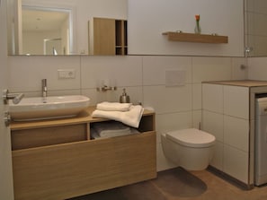 A modern bathroom with a large sink, a toilet, and a mirror. - Rebenrain Comfortable Holiday Residence (Steinach)