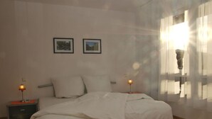 A bedroom with a bed, two bedside tables, a window with curtains, and two framed pictures on the wall. - Rebenrain Comfortable Holiday Residence (Steinach)
