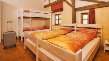 A room with two bunk beds, a suitcase, and a small table.