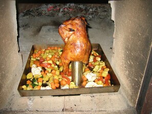 A roasted chicken on a spit with a tray of vegetables underneath. - Oberprill Modern Retreat (Loitzendorf)