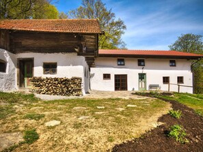A rustic building with a red-tiled roof and white walls, featuring a wooden door and windows, and a stack of firewood in front. - Oberprill Modern Retreat (Loitzendorf)