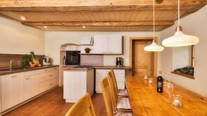 A modern kitchen with wooden cabinets, a central island, and a dining area with a wooden table and chairs. - Oberprill Modern Retreat (Loitzendorf)
