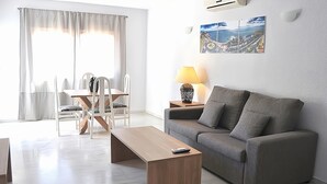 Una sala de estar moderna con un sofá, una mesa de centro de madera, una mesa de comedor con sillas y una lámpara.