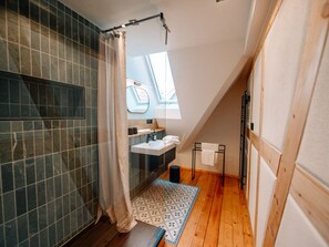 Et moderne badeværelse med bruser, vask og et vindue.