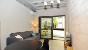 Quarto moderno com sofá, mesa redonda e televisão sobre um suporte de madeira.