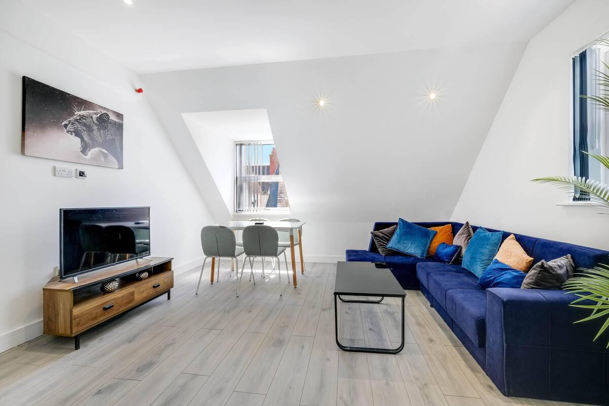 Uma sala de estar moderna com televisão, sofá, mesa de centro e área de jantar.