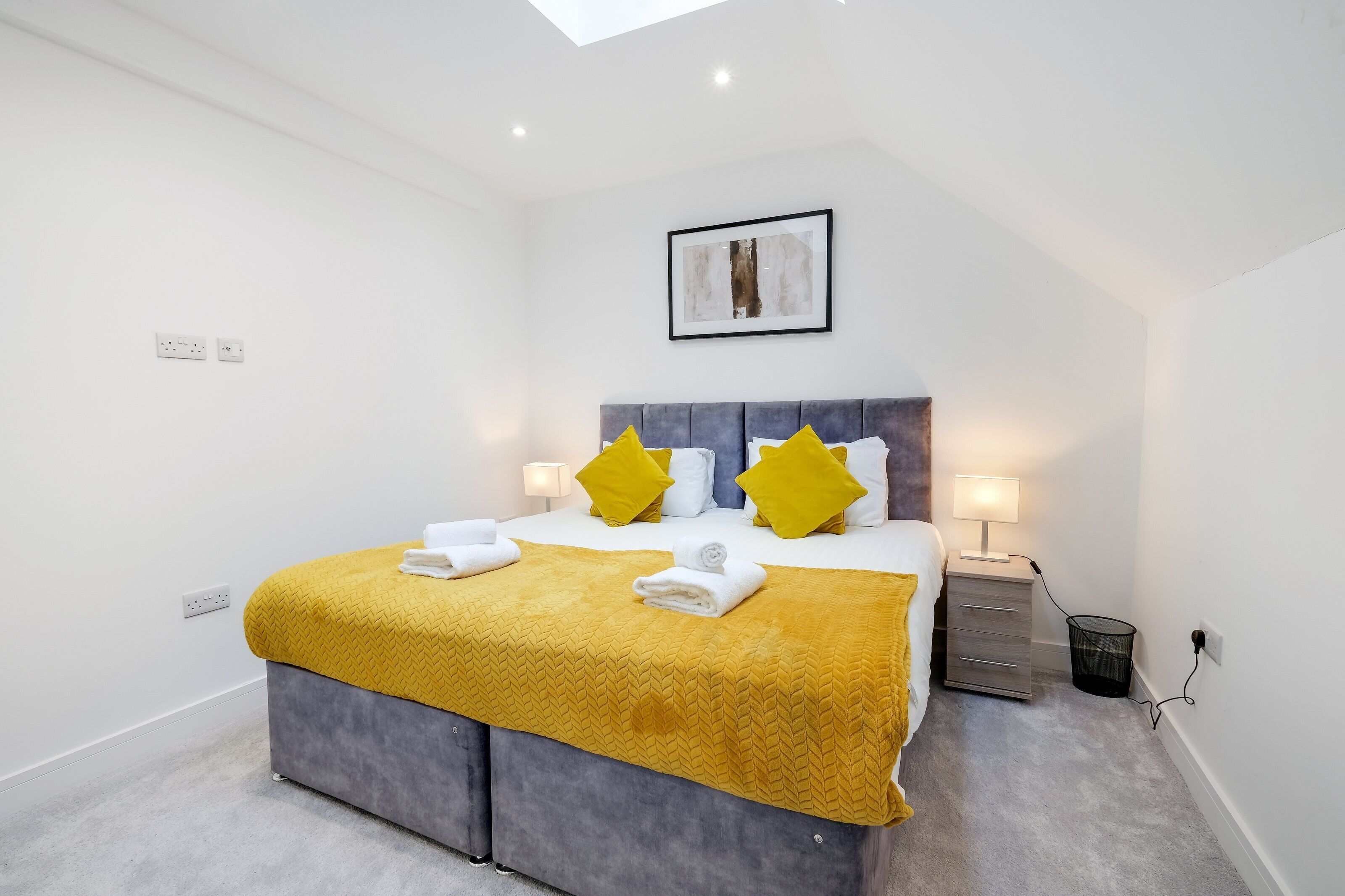 Une chambre d’hôtel moderne équipée d’un lit, de lampes de chevet, d’une petite table et d’une prise de courant.