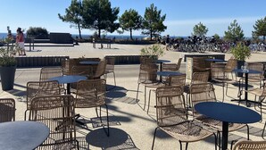 An outdoor seating area with wicker chairs and tables, overlooking a beach and a parking area with bicycles. - CÉLADON - Studio, Rez-de-Jardin, Proche Plage - U205 (Carnac)