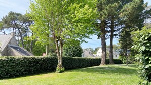 A grassy area with trees and a hedge, houses in the background, and a clear sky. - CÉLADON - Studio, Rez-de-Jardin, Proche Plage - U205 (Carnac)