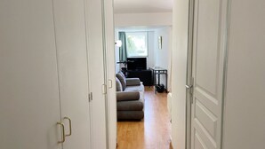 A hallway leading to a living area with a sofa, a small table, and a TV. - CÉLADON - Studio, Rez-de-Jardin, Proche Plage - U205 (Carnac)