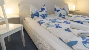 Quarto bem arrumado com uma cama, uma cadeira e mesas de cabeceira.