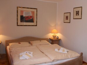 A double bed with beige bedding, a bedside table with a lamp, and a framed picture on the wall. - Holiday Apartment Seagull (Bad Saarow)