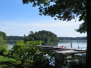 A dock extending into a calm lake surrounded by lush greenery and a forested hill in the background. - Holiday Apartment Seagull (Bad Saarow)