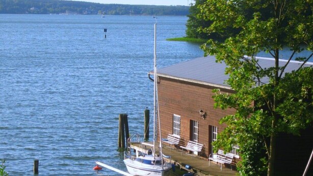 Un muelle con un barco, un edificio de ladrillo y un lago tranquilo.