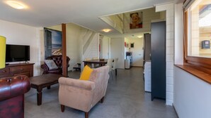 A spacious living area with a sofa, coffee table, and a television. There is a staircase leading to an upper level.