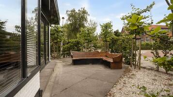 A modern outdoor seating area with a bench, a paved walkway, and a building with large windows.