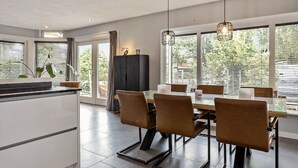 A modern kitchen with a dining area, large windows, and a view of greenery outside. - Holiday Home With a Garden and Parking (Drachten)