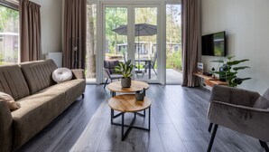 Una sala de estar moderna con sofá, sillón, mesa de centro y televisor.