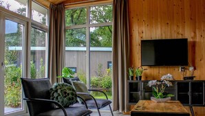 Un salón moderno con ventanas amplias, un televisor de pantalla plana e interiores de madera.